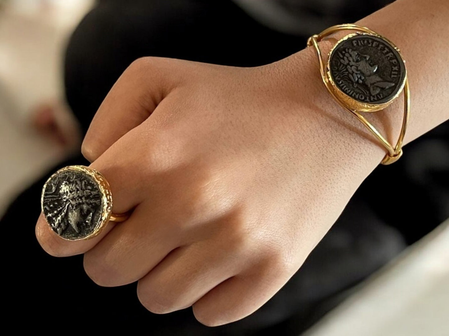 a close up of a person wearing a ring with a coin on it