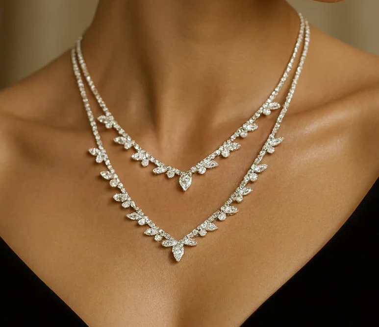 Two layered diamond-studded leaf-pattern necklaces forming a V on a model's neck.